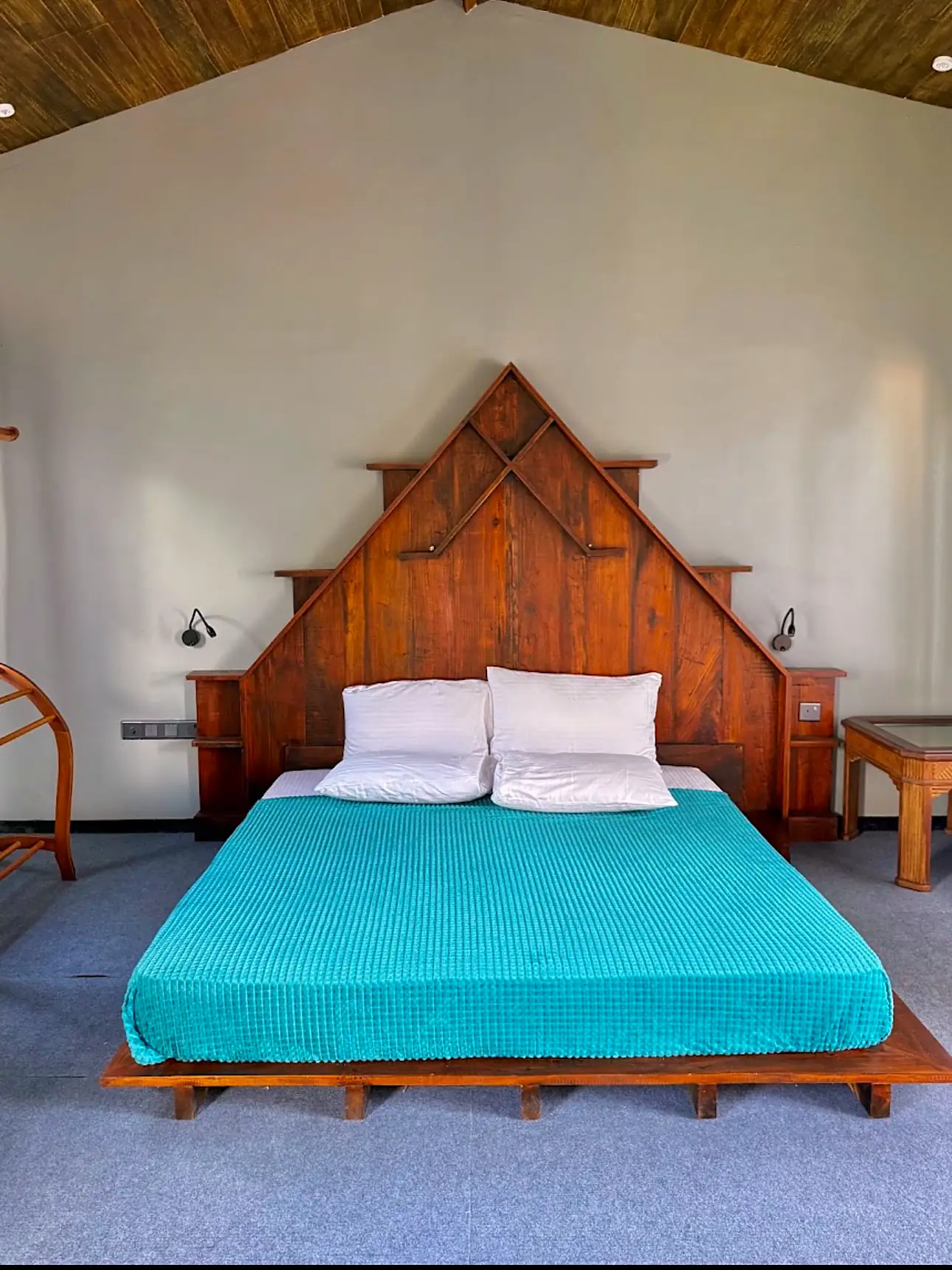 King bed with hand-built timber headboard under a wooden ceiling at CanRoyal Resort, Tangalle