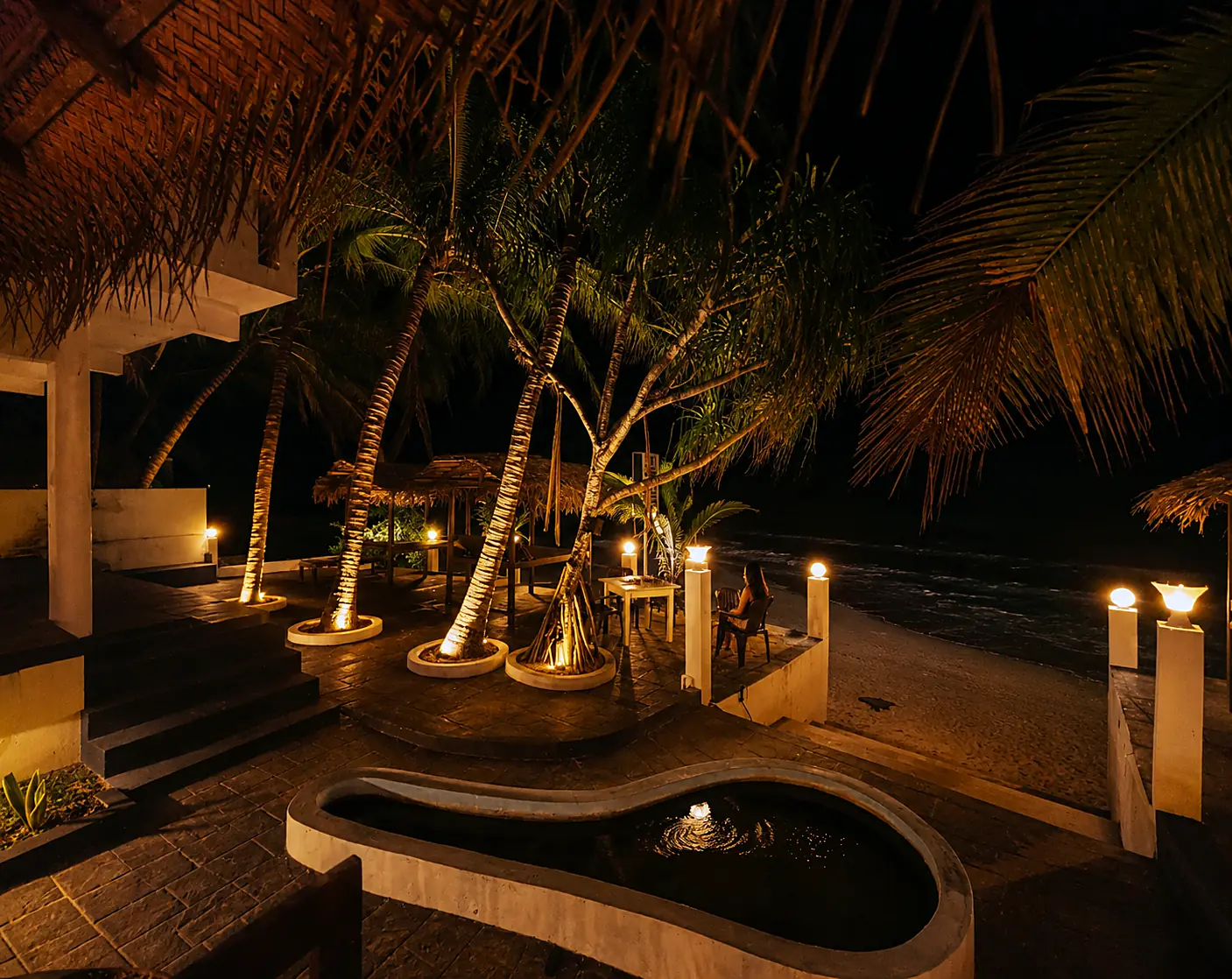 Lamplit terrace and palms at CanRoyal Resort, Tangalle, after dark